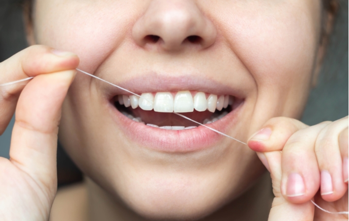 A woman flossing to help prevent her gums from bleeding