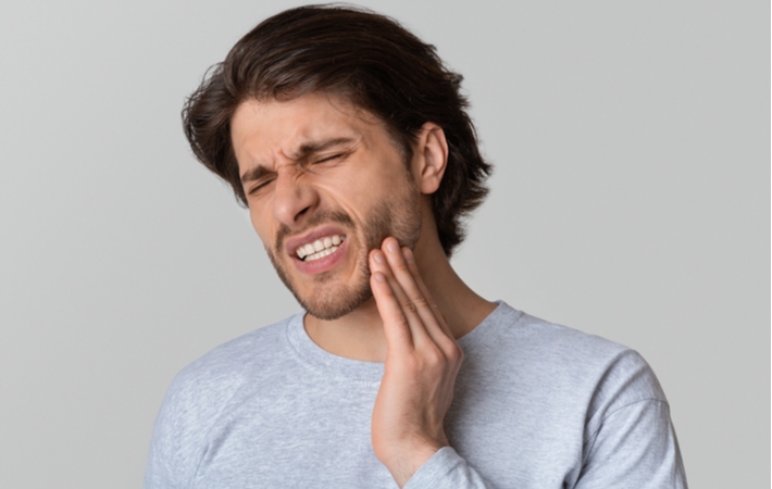 A man holding his cheek in pain due to an infected tooth