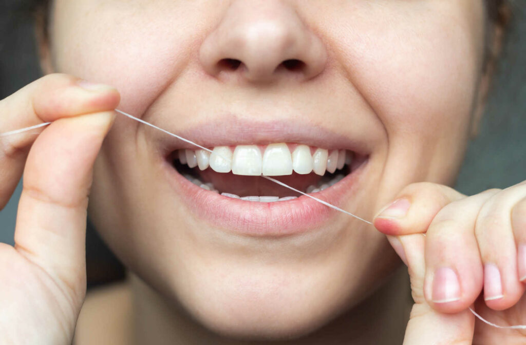 A close up of a person flossing their teeth to maintain good oral health.