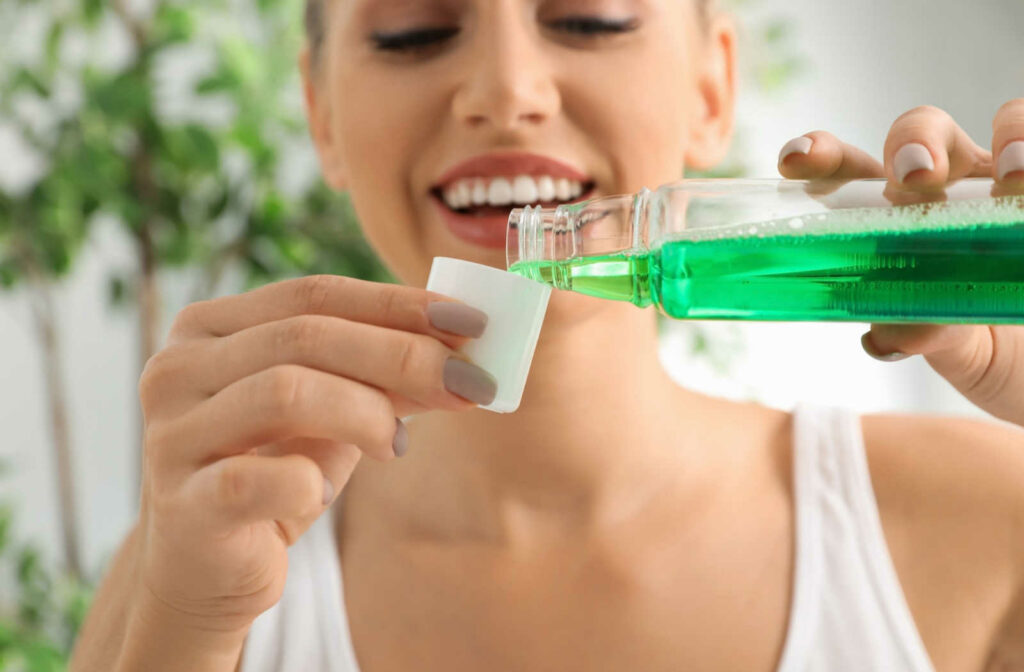 A woman pouring mouthwash into the cap after brushing and flossing her teeth to maintain good oral health