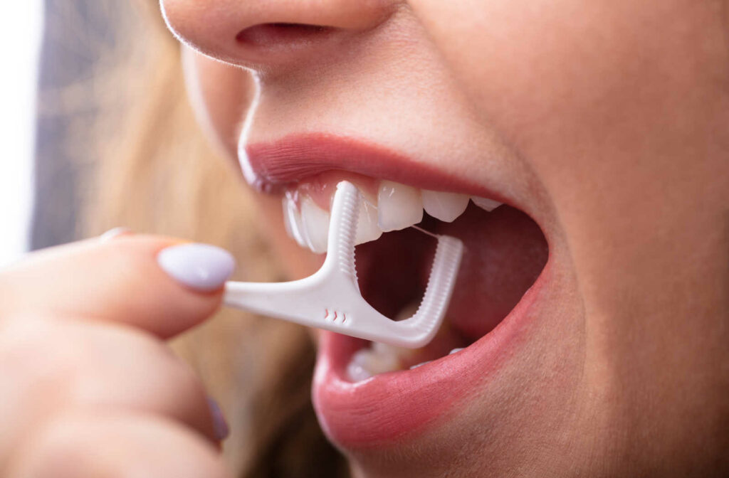 A close up of a person using a flossing pick as an alternative to flossing
