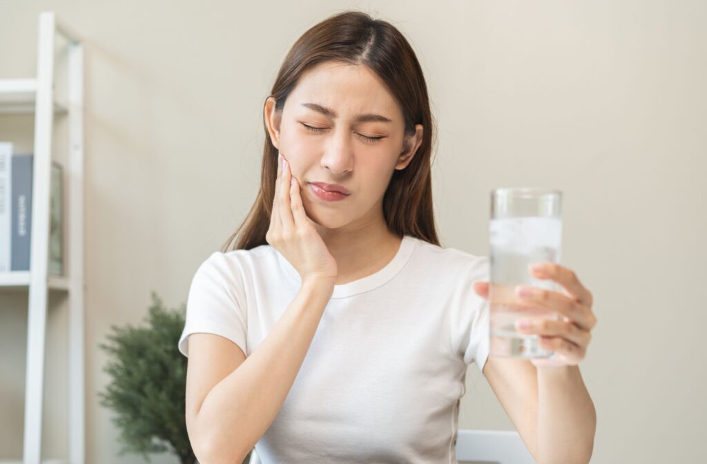 A woman experiencing tooth pain after drinking cold water.