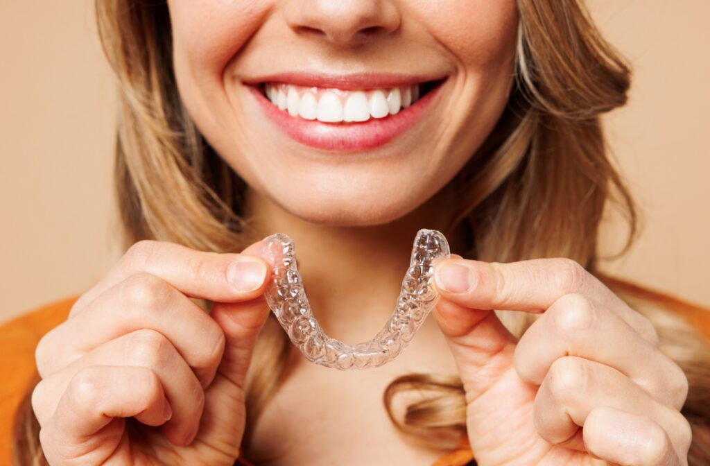 A woman is holding an invisalign tray.