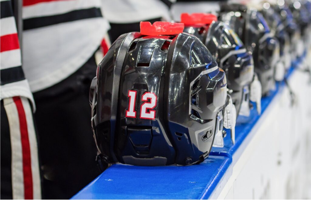 A close up of a hockey player's helmet with a mouthguard sitting on top of the helmet, an important piece of equipment to protect the teeth