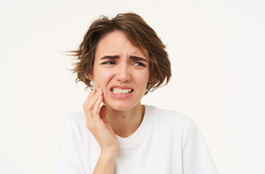 A young adult rubbing their jaw in discomfort from the pain of a cracked tooth.