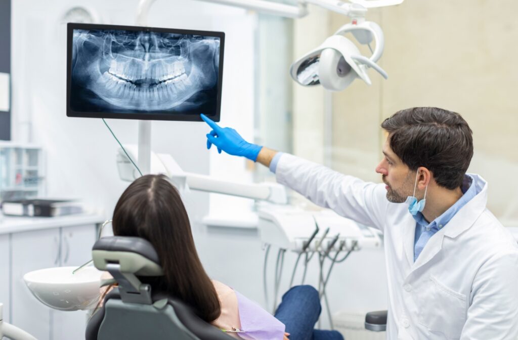 A dentist pointing to a patient's x-ray