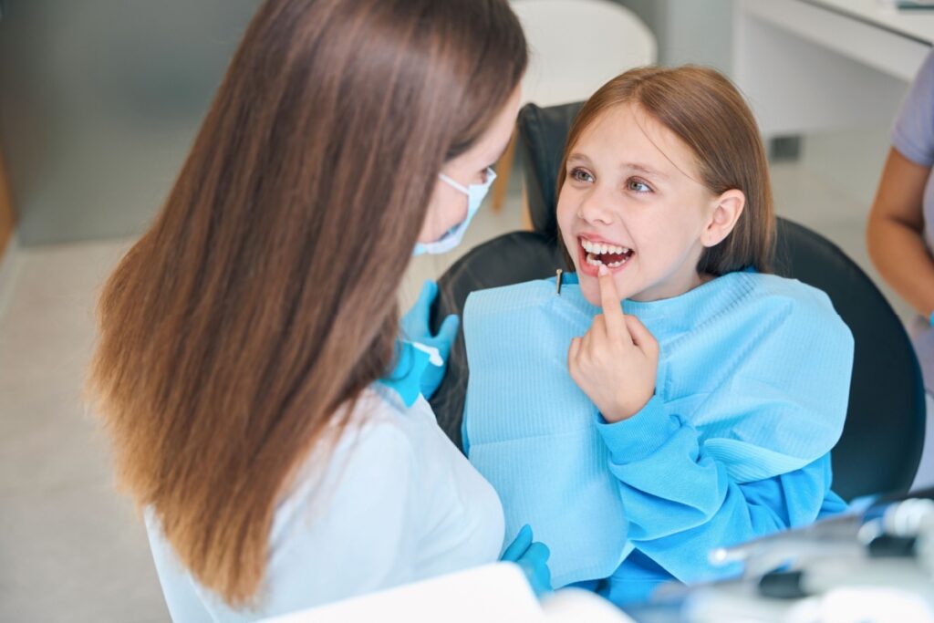 A young child showing her lost tooth to the dentist at a dental clinic.