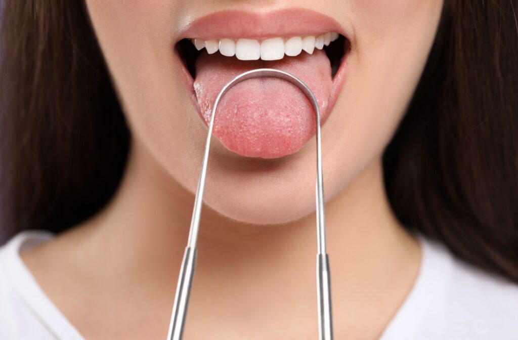 A close up of a person using a tongue scraper as part of their oral health care routine.