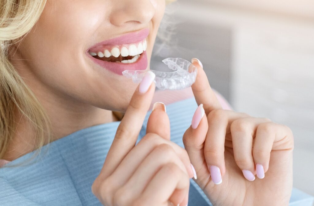 A patient at the dental office putting in a new set of Invisalign clear aligners to help straighter their teeth and correct their bite.